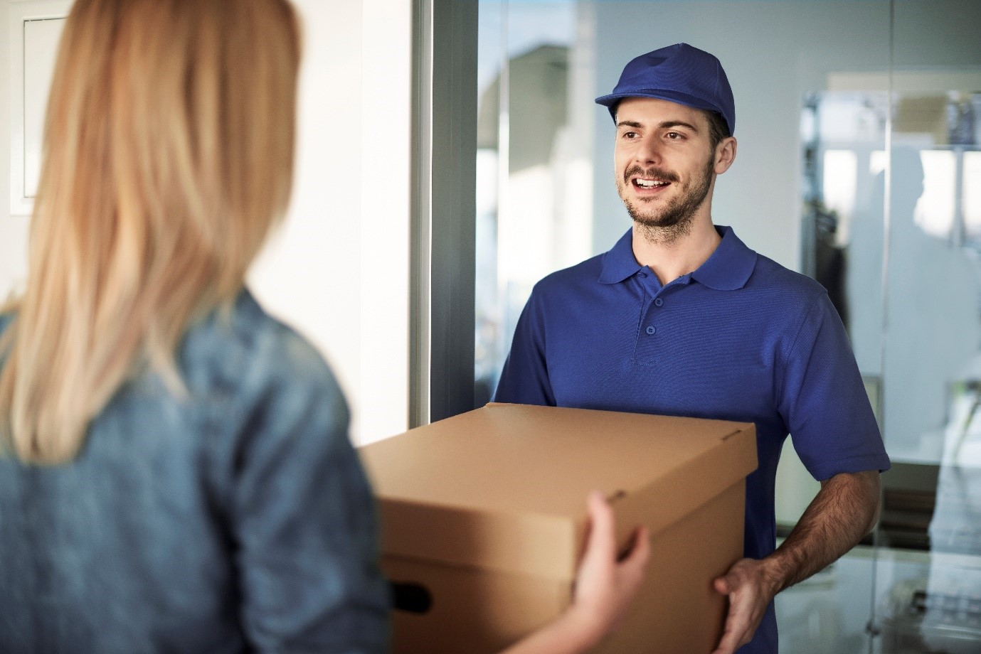 delivery driver delivering boxed package to lady in an office environment